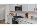 Gourmet kitchen boasts stainless steel appliances, gas range, quartz countertops, and stylish tile backsplash at 82 Fairwinds Dr, Lillington, NC 27546