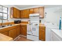 Functional kitchen with wood cabinets, basic appliances, and a sink near a window, plus a nearby washer and dryer at 100 Forsyth Dr, Chapel Hill, NC 27517