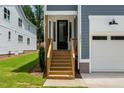 Close-up of the front entrance, displaying a black front door with wooden stairs and handrails at 1211 Chaney Rd, Raleigh, NC 27606