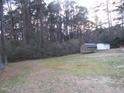 Large backyard surrounded by mature trees, with outbuildings providing ample storage at 2506 Poole Rd, Raleigh, NC 27610