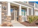 Close-up of the inviting front porch with stone accents, white pillars, and well-maintained landscaping at 2561 Summersby Dr, Mebane, NC 27302