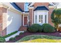 Close-up of the home's entrance featuring a bay window, brick facade, and meticulously maintained landscaping at 2909 Hawtree Dr, Raleigh, NC 27613