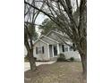 A quaint single-story home with neutral siding, accented by black shutters and green shrubbery near the front entrance at 309 Gladstone Dr, Durham, NC 27703
