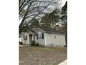 Single-story home shows a side angle with neutral siding and black shutters, set on a partially shaded lot with mature trees at 309 Gladstone Dr, Durham, NC 27703