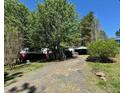 View of the house from the driveway with mature trees and shrubbery at 328 Cone Dr, Henderson, NC 27537