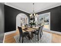 Elegant dining room showcasing dark walls, hardwood floors, a large window and stylish chandelier at 4501 Bartlett Dr, Raleigh, NC 27609