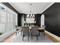 Chic dining room featuring dark walls, hardwood floors, chandelier and large window at 4501 Bartlett Dr, Raleigh, NC 27609