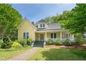 Charming yellow home featuring a welcoming front porch and well-maintained landscaping at 531 N Main St, Graham, NC 27253