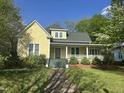 Charming yellow home featuring a welcoming front porch and well-maintained landscaping at 531 N Main St, Graham, NC 27253