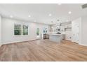 Open-concept living space with kitchen island and wood-look floors, bathed in natural light from large windows at 624 Brittany Ct, Durham, NC 27703