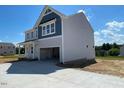 Side view of the home displaying gray siding and showing the concrete driveway leading to the two-car garage at 108 Grove Township Way, Angier, NC 27501