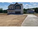 View of the home featuring a two-car garage and a concrete driveway with a neighboring home being built nearby at 108 Grove Township Way, Angier, NC 27501