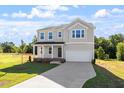 Two-story home featuring an attached garage, well-manicured lawn, and charming front porch at 119 Grove Township Way, Angier, NC 27501