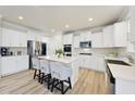 Open kitchen boasts stainless steel appliances, white cabinetry, large island, and hardwood floors at 130 Silent Brook Trl, Franklinton, NC 27525
