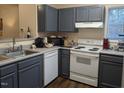 The gray kitchen features a sink, stove, dishwasher, and ample counter space with wood-look flooring at 1911 Wolftech Ln # 303, Raleigh, NC 27603