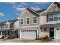 Charming two-story home with a white garage door, neat landscaping and blue skies at 1952 Grassy Banks Dr, Raleigh, NC 27610