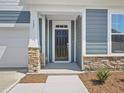 Inviting covered entryway with stone accents, a black front door, and crisp white trim at 121 Willow Cameron Way, Angier, NC 27501