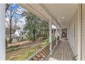 Inviting covered porch with wooden floors and railing, providing ample space for relaxing and enjoying the view at 206 Spring Ln, Chapel Hill, NC 27514