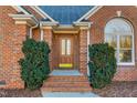 Inviting front entrance with a beautiful wooden door, red brick, trimmed shrubs and brick steps at 2318 Rogers Rd, Graham, NC 27253