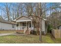 Quaint home featuring a covered front porch, neutral siding, and mature trees at 2513 Drexall Ave, Durham, NC 27704