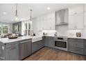 Modern kitchen boasts gray and white cabinets, stainless steel appliances, a farmhouse sink, and stylish pendant lighting at 4095 Elk Crk Ln, Raleigh, NC 27612