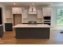Modern kitchen features stainless steel appliances, a central island, and sleek white and gray cabinetry at 104 Pointe Park Cir, Holly Springs, NC 27540