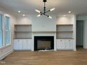 Bright living room featuring a fireplace, built-in cabinets, open shelves, and modern lighting at 104 Pointe Park Cir, Holly Springs, NC 27540