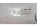 Open-concept living room boasting plentiful windows, lots of natural light, and access to the back porch at 104 Pointe Park Cir, Holly Springs, NC 27540