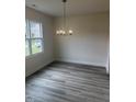 Dining area featuring luxury vinyl plank flooring, a modern chandelier and natural light from a large window at 122 Reece Dr, Sanford, NC 27332