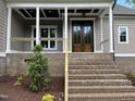 Front entrance with brick steps leading to a covered porch and a wooden double door at 165 Cotton Fields Ln # 25, Fuquay Varina, NC 27526
