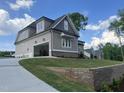 A view from the side showing an open garage and driveway leading up to a grey and beige house at 165 Cotton Fields Ln # 25, Fuquay Varina, NC 27526