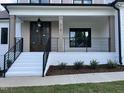 Inviting front porch featuring a brick foundation, iron railings, and a stylish front door, surrounded by neat landscaping at 318 Deer Tail Ln # 35, Fuquay Varina, NC 27526