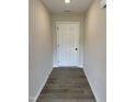 Entryway hallway with modern gray wood flooring, light gray walls, and a white door at 39 N Movado Trl, Kenly, NC 27542
