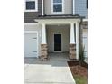 Inviting front porch with stone pillars and a black front door creates a charming entryway at 605 Leland Hl Cir, Zebulon, NC 27597
