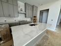 Modern kitchen featuring gray cabinets, island with sink, and designer backsplash at 63 Daybreak Way, Fuquay Varina, NC 27526