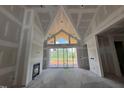 Bright living room with tall ceilings, fireplace, and sliding glass doors showcasing the yard at 63 Daybreak Way, Fuquay Varina, NC 27526