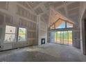 Spacious living room featuring high ceilings, fireplace, and sliding glass doors to backyard at 63 Daybreak Way, Fuquay Varina, NC 27526