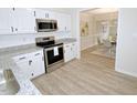 Bright kitchen featuring white cabinets, granite countertops, stainless steel appliances, and wood-look flooring at 6525 New Market Way, Raleigh, NC 27615