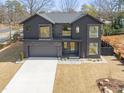 A modern two-story gray home with an attached garage, well-manicured lawn, and a view of the landscape at 838 Woodburn Rd, Raleigh, NC 27605