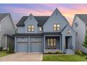 Beautiful, two-story home featuring gray siding, black trim, two-car garage, and charming front porch at sunset at 183 Post Oak Rd, Chapel Hill, NC 27516
