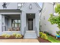 Close-up of charming front porch featuring a brick facade, modern front door, and cozy seating area at 183 Post Oak Rd, Chapel Hill, NC 27516