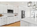 Modern kitchen featuring white cabinets, stainless steel appliances, a large island, and hardwood floors at 2021 Rockwall Farms Ln, Fuquay Varina, NC 27526