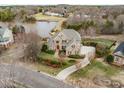 Stunning aerial view of a brick home near a lake, surrounded by green lawns, offering a picturesque setting at 210 Lake Manor Rd, Chapel Hill, NC 27516