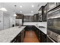 Modern kitchen featuring granite countertops, dark cabinets, and stainless steel appliances at 357 Roberts Ridge Dr, Cary, NC 27513