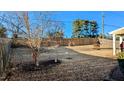 Fenced backyard features winter dormant grass and a mature tree with bare branches under a clear blue sky at 508 Stapleford Ln, Fuquay Varina, NC 27526