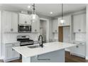 This modern kitchen features sleek white cabinets, stainless steel appliances, an island and pendant lighting at 73 Merle Dr, Wendell, NC 27591