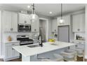 The kitchen boasts modern white cabinets, stainless steel appliances, a quartz island with seating and pendant lights at 73 Merle Dr, Wendell, NC 27591