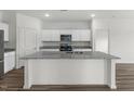 Bright kitchen featuring white cabinets, a granite countertop island, and modern appliances at 209 Swift Park Dr, Zebulon, NC 27597