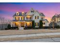 Beautiful two-story home with manicured lawn, covered porch, and warm exterior lighting at twilight at 5025 Fanyon Way, Raleigh, NC 27612