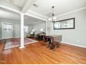 Open living room with hardwood floors, columns, neutral walls, and a dining table at 6469 New Market Way, Raleigh, NC 27615